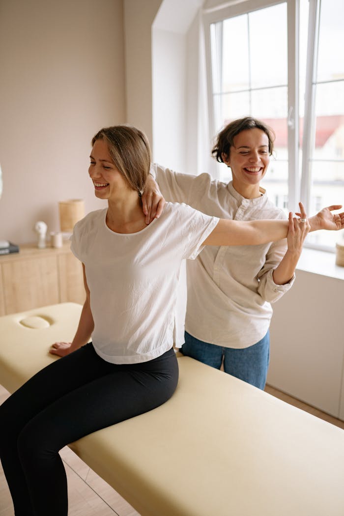 The Art of Drawing Readers In: Your attractive post title goes here A therapist guides a woman in a stretching exercise on a massage table in a clinic setting.